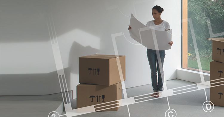 SS21 054 Area och volym för byggnader En kvinna som står upp i ett tomt rum med några kartonger och tittar på en ritning
